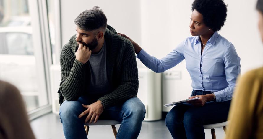 African American psychotherapist encouraging a man to talking about his problems during group therapy.
